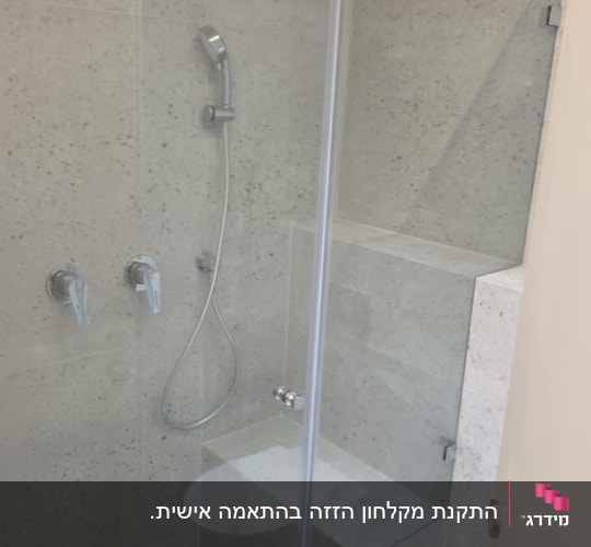 מקלחת עם דלת זכוכית, ראש מקלחת ומגבת ירוקה